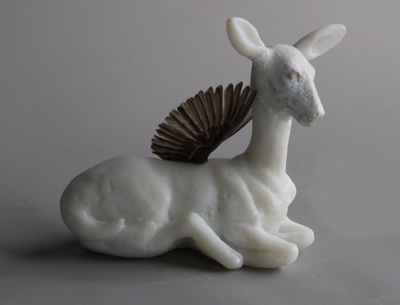 a glass sculpture of a deer with a small wing